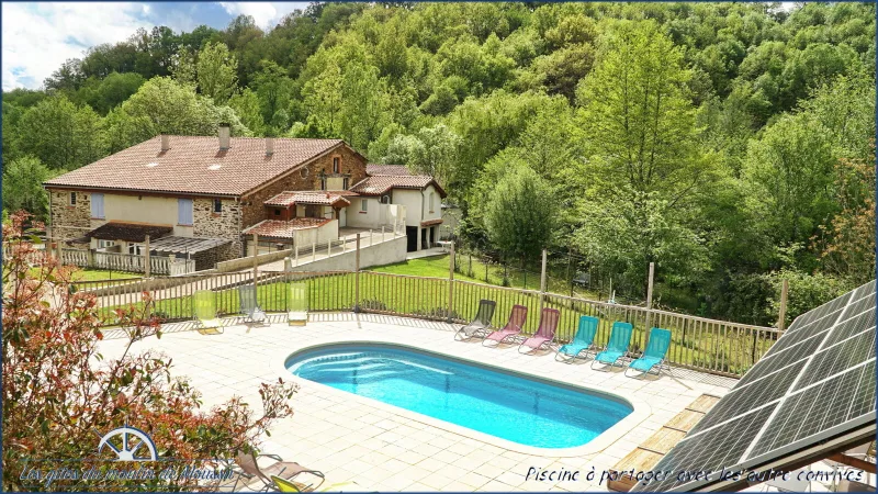 Piscine entourée de transats colorés avec vue sur la façade en pierre