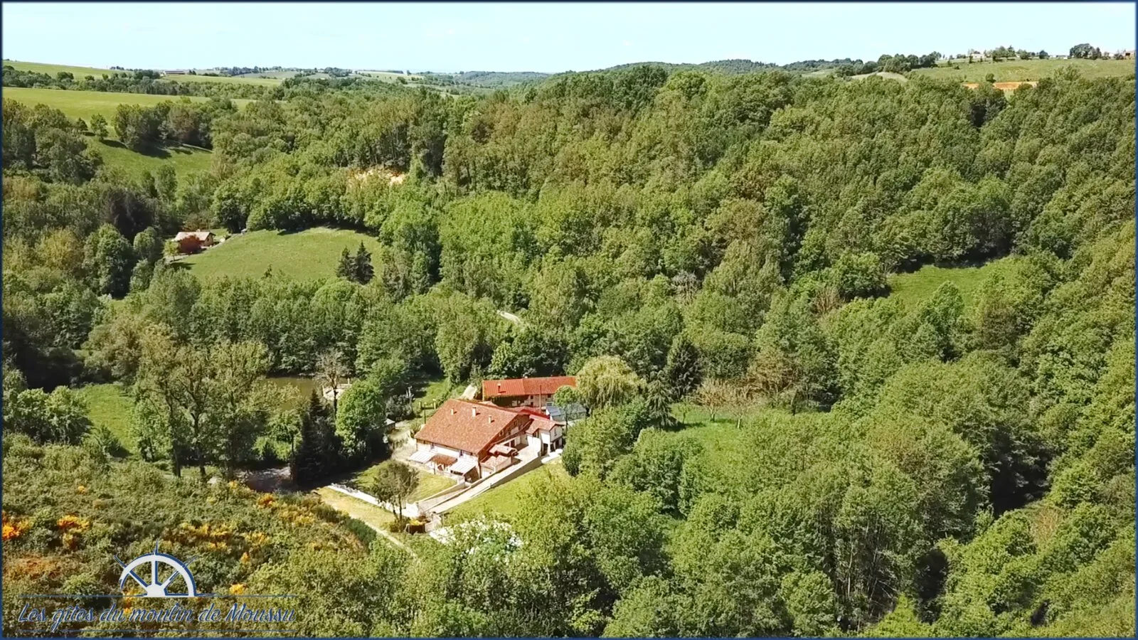 Gîte de groupe Grange des 15 Meuniers à Villefranche-d'Albigeois — Vue aérienne de la grange en pierre nichée dans un vallon boisé, capacité 15 personnes