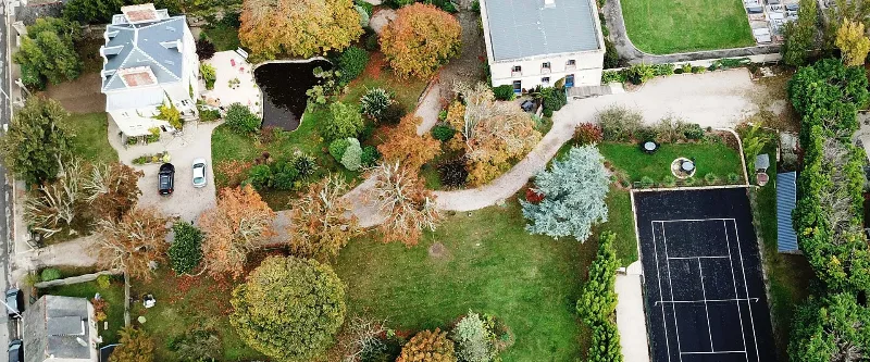Vue aérienne de la propriété avec jardin arboré, étang et court de tennis