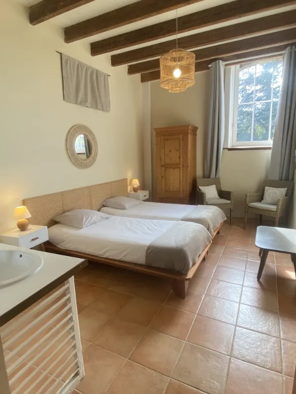 Chambre avec deux lits jumeaux sous poutres apparentes
