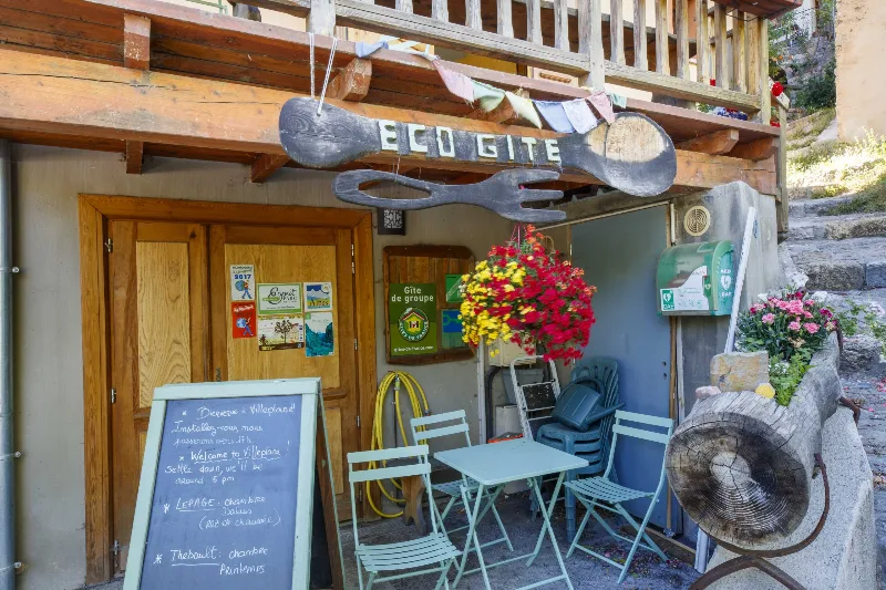 Façade de l'écogîte en pierre et chaux colorée avec ses balcons en bois, entourée de nature