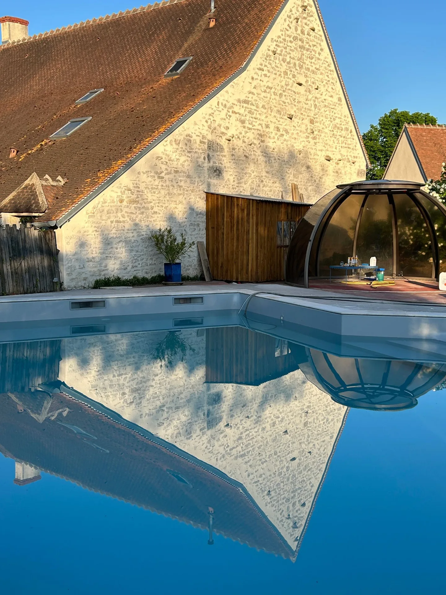 Gîte de groupe Gîte des Brunettes à Farges-Allichamps — Façade en pierre du gîte reflétée dans la piscine, toiture berrichonne traditionnelle, capacité 19 personnes