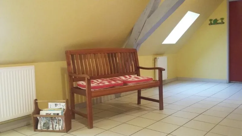 Coin salon sous les combles avec banquette en bois et panier à journaux