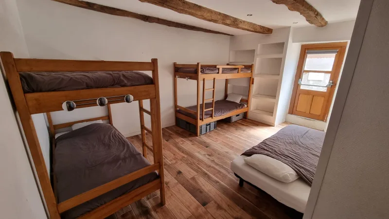 Chambre avec lits superposés en bois et poutres apparentes, ambiance conviviale pour les groupes