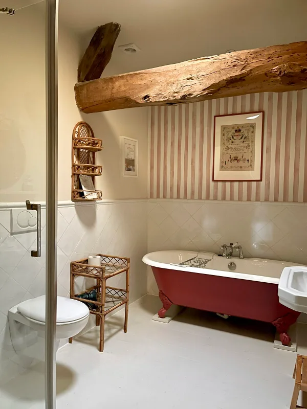 Salle de bain rétro avec baignoire ancienne sur pieds et poutre apparente