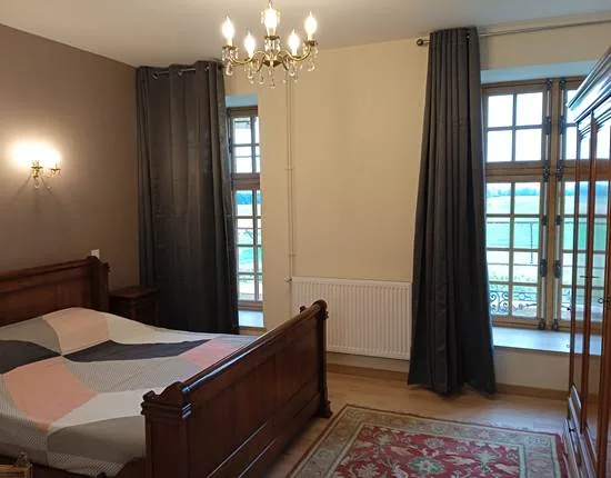 Chambre élégante avec lit en bois sculpté, lustre et grandes fenêtres à petits carreaux