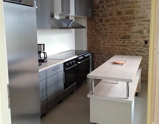 Cuisine moderne équipée avec mur en pierre apparente et îlot central