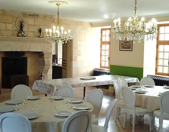 Grande salle à manger voûtée avec cheminée en pierre et lustres à pampilles