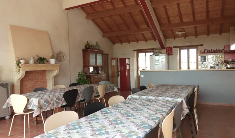 Grande salle à manger cathédrale avec cheminée en pierre, poutres apparentes et coin cuisine