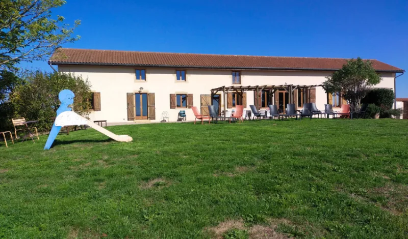 Façade en pierre de la longère du 19e siècle avec terrasse ombragée sous pergola et jardin