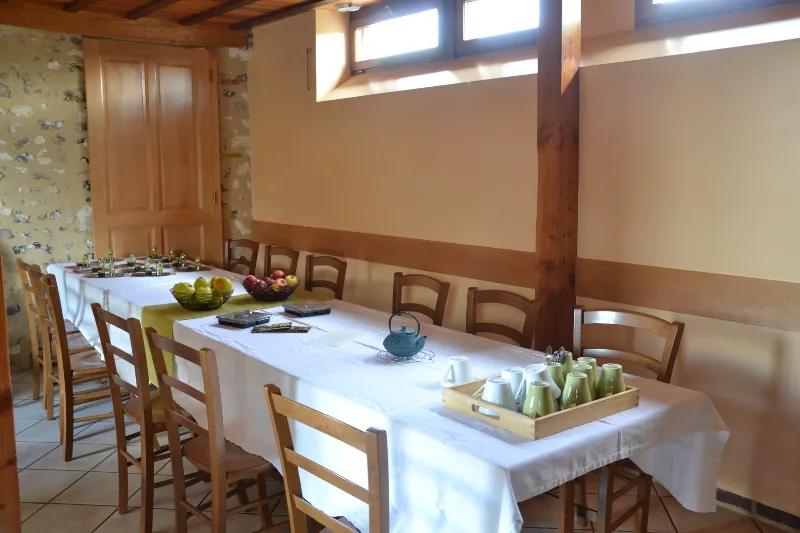 Grande salle de réception avec longue table dressée pour les repas de groupe