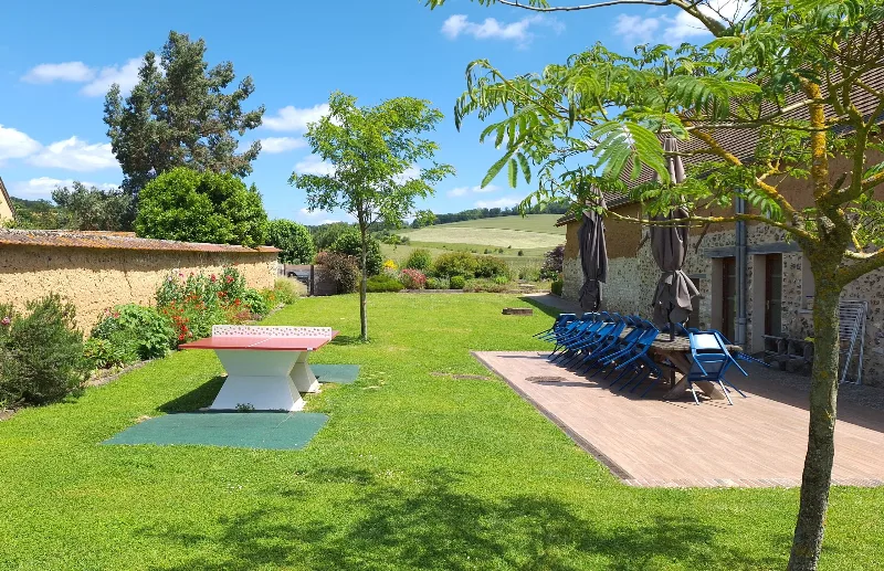 Terrasse en bois du gîte avec grande table conviviale et vue sur la campagne normande