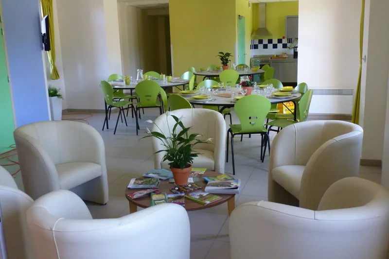 Coin salon avec fauteuils blancs, table basse et vue ouverte sur la salle à manger