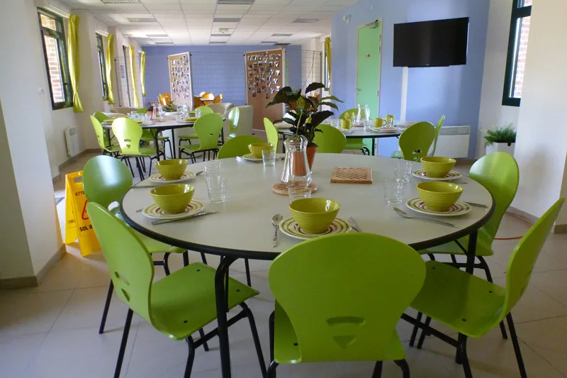 Salle à manger commune avec tables rondes dressées pour les repas de groupe