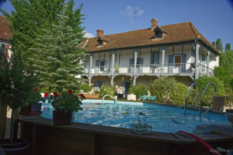 Vue de la maison de maître depuis la piscine entourée d'un jardin fleuri
