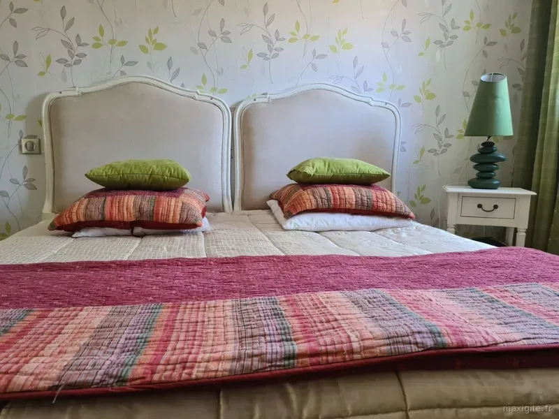 Chambre double avec têtes de lit capitonnées et linge de lit fleuri