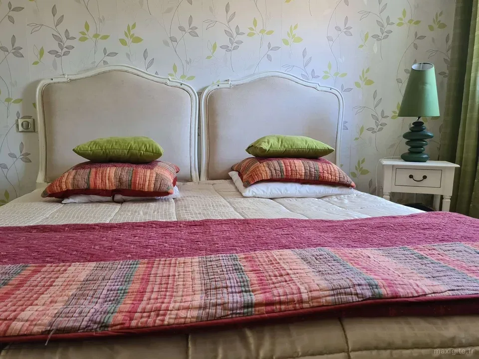 Chambre double avec têtes de lit capitonnées et linge de lit fleuri