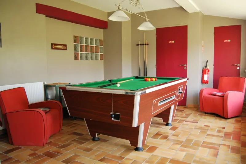 Salle de billard et jeux avec fauteuils rouges pour les soirées entre amis