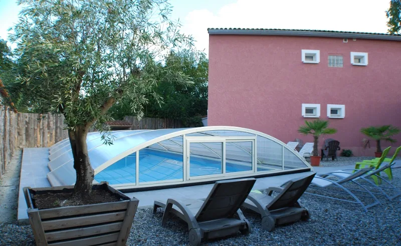 Façade de la maison avec piscine couverte et terrasse en galets
