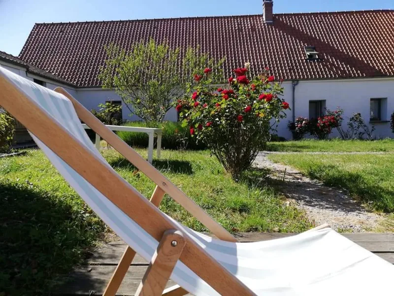 Terrasse extérieure avec chaise longue face à la façade en pierre du gîte