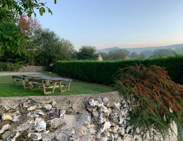 Table de pique-nique en bois installée dans le jardin bordé de haies champêtres