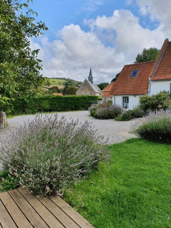 Vue sur le jardin clos avec le clocher du village visible au loin, ambiance champêtre
