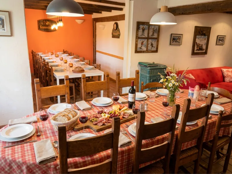 Grande salle à manger avec longues tables en bois pour accueillir un groupe nombreux