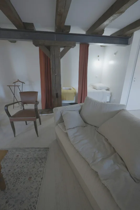 Séjour lumineux avec canapé, fauteuil en cuir et vue sur une chambre à l'arrière-plan