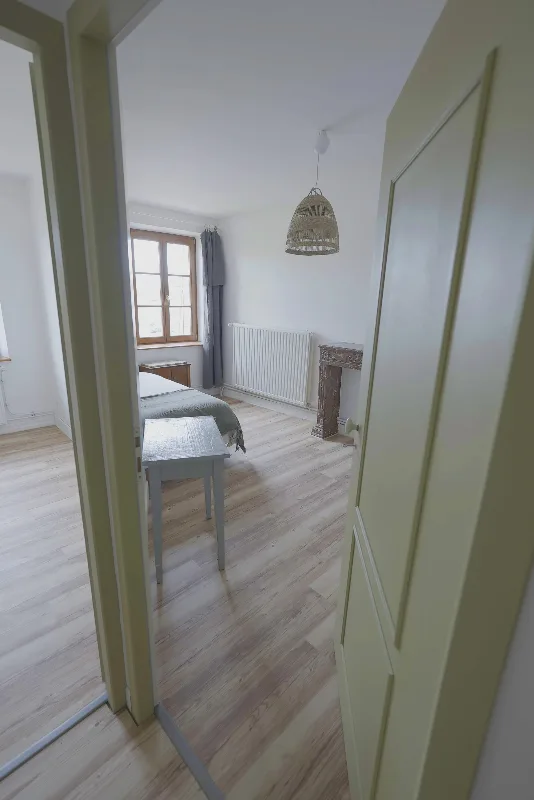 Chambre avec lit simple, cheminée en pierre ancienne et fenêtre donnant sur la campagne