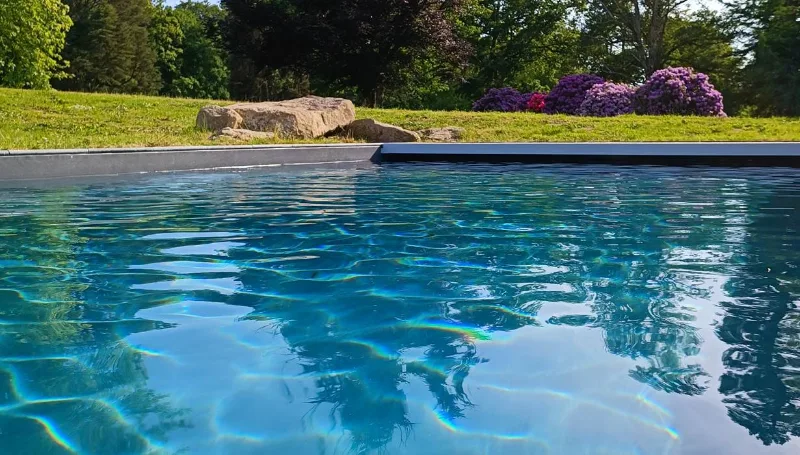 Piscine chauffée en bordure de pelouse avec vue sur la façade du château