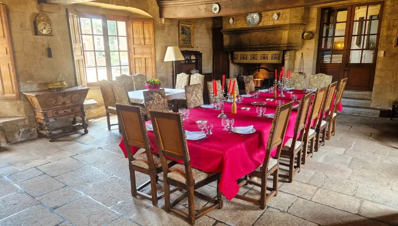 Grande salle à manger voûtée avec cheminée en pierre et longue table dressée