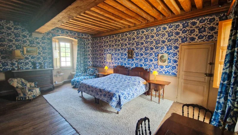 Chambre à motifs bleus avec grand lit à baldaquin et poutres apparentes