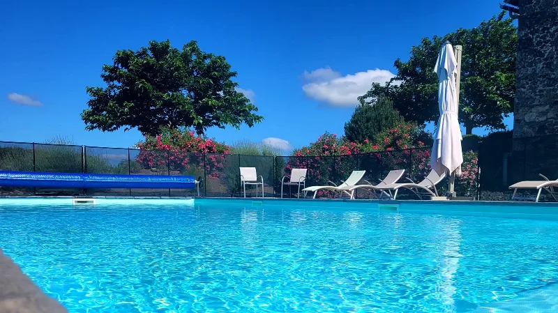 Piscine chauffée et sécurisée entourée de transats et d'un parasol