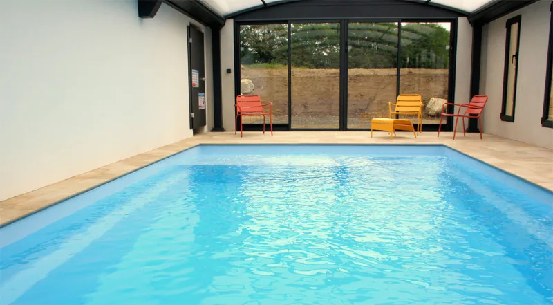 Piscine intérieure chauffée avec baie vitrée donnant sur la terrasse