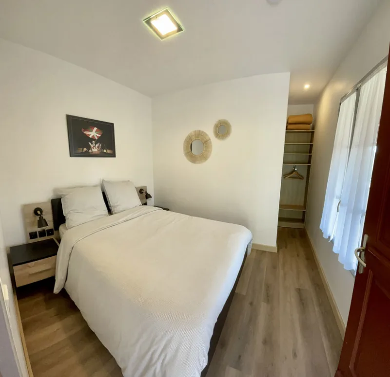 Chambre double avec parquet clair, miroirs ronds et dressing ouvert