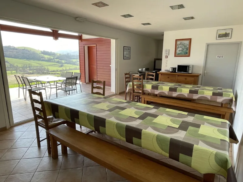 Grande salle à manger commune avec longues tables et vue panoramique sur la vallée