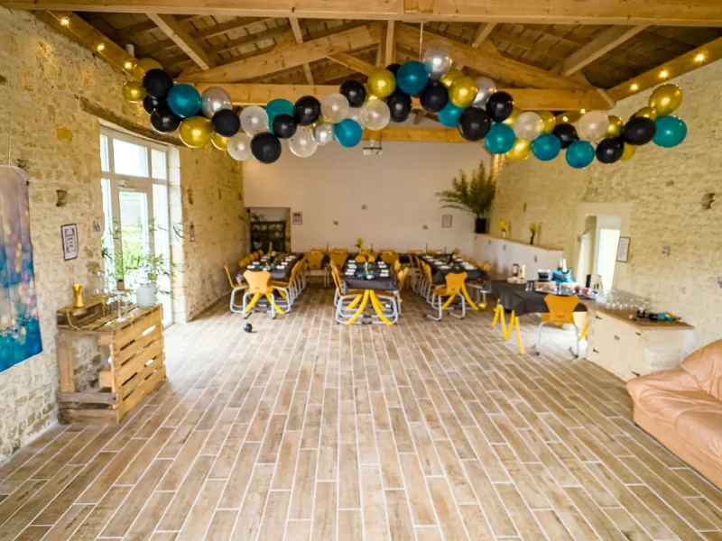 Salle de réception avec charpente en bois apparente et grandes tables dressées