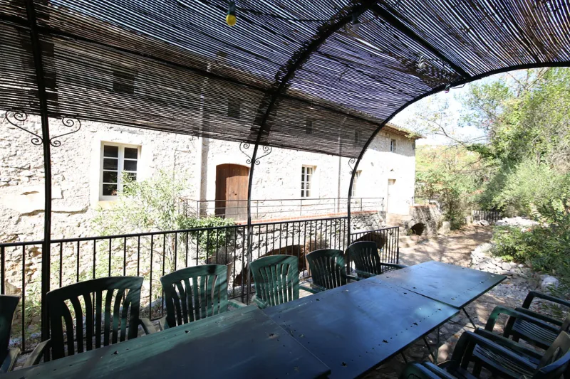 Terrasse couverte en pergola avec grande table en bois pour les repas en groupe