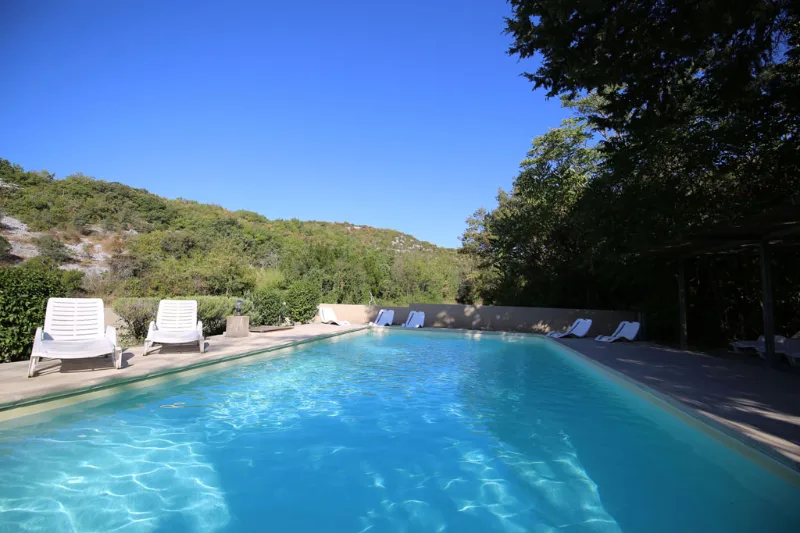 Piscine extérieure entourée de transats avec vue sur les collines boisées
