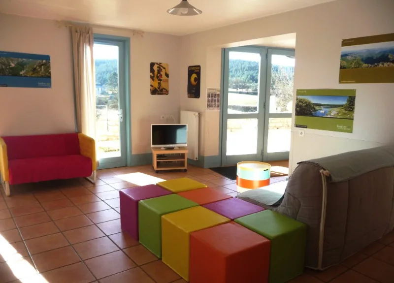 Salon coloré avec canapés et poufs cubes multicolores, baies vitrées sur la campagne