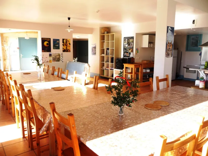 Grande salle à manger avec longues tables en bois pour les repas de groupe