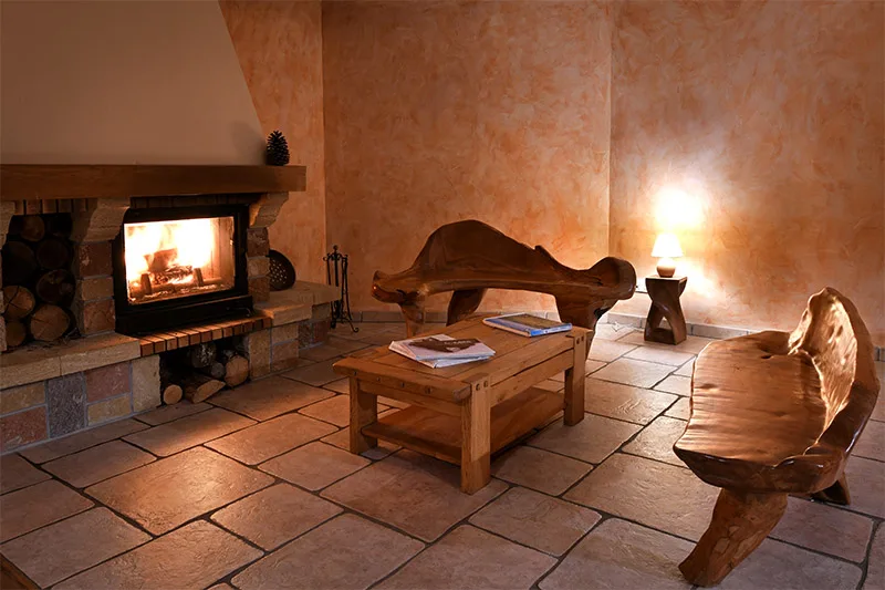 Coin cheminée cosy avec feu de bois et mobilier en bois brut sculpté