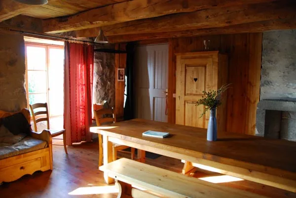 Salle à manger montagnarde avec longue table en bois, banc et cheminée en pierre