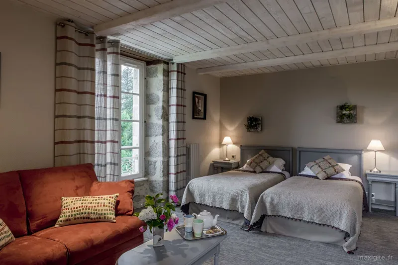 Chambre confortable avec deux lits, canapé et poutres apparentes au plafond