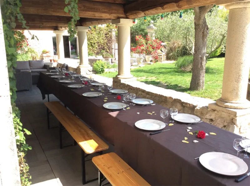 Longue table dressée en extérieur sous une pergola pour les repas de groupe