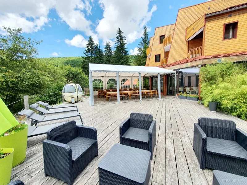 Façade du chalet de montagne avec grande terrasse en bois équipée d'un salon d'extérieur