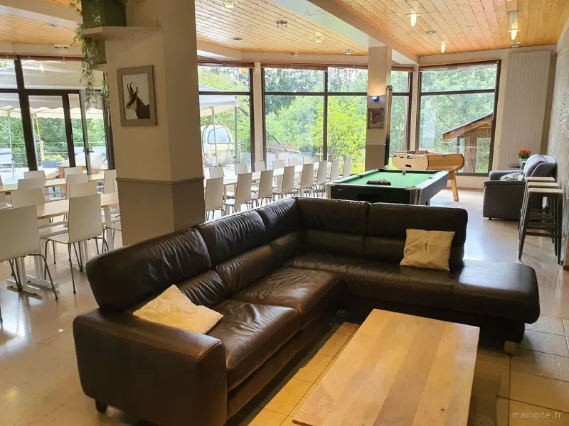Second salon avec canapés en cuir et vue sur la forêt environnante