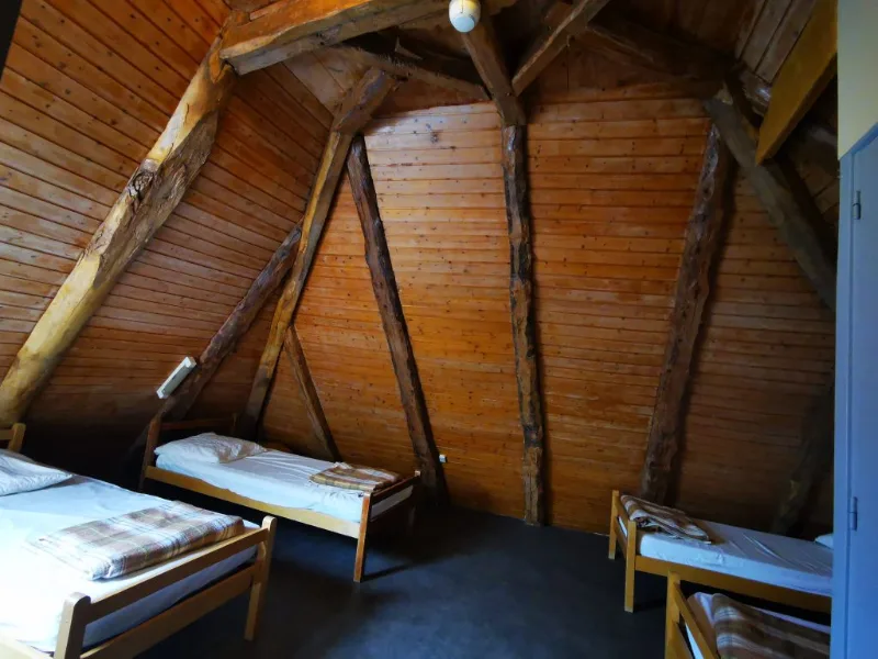 Chambre mansardée sous charpente en bois apparente avec plusieurs lits simples