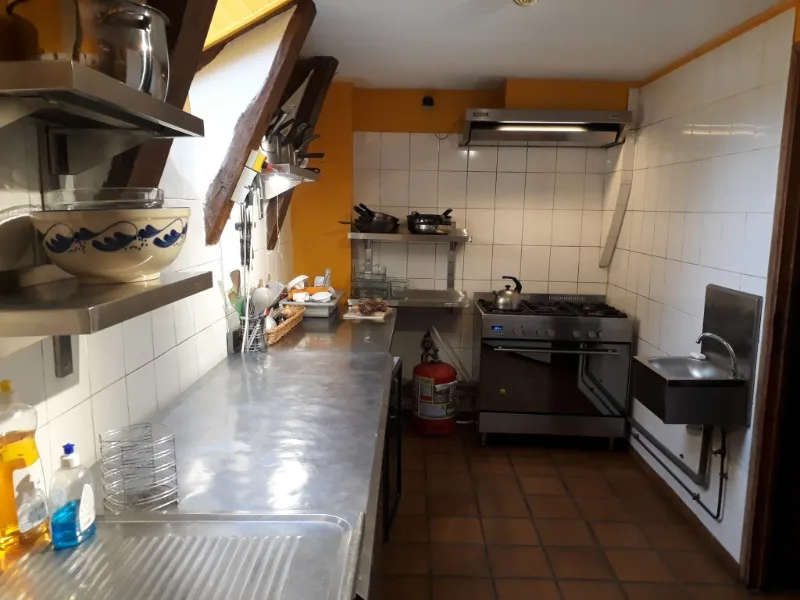 Cuisine équipée avec plaques de cuisson, hotte professionnelle et plan de travail en inox