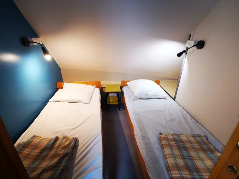 Chambre avec deux lits simples séparés par une table de nuit et lampes de chevet